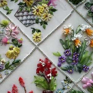 K&ouml;nnte beinhalten: Nahaufnahme einer Blumenstickerei mit verschiedenen Blumen in Gelb, Lila, Rosa und Rot. Die Blumen sind in einem Gittermuster mit silbernen Akzenten angeordnet. Die Stickerei zeigt detaillierte Bandarbeiten.