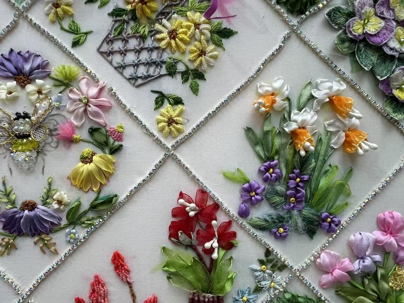 K&ouml;nnte beinhalten: Nahaufnahme einer Blumenstickerei mit verschiedenen Blumen in Gelb, Lila, Rosa und Rot. Die Blumen sind in einem Gittermuster mit silbernen Akzenten angeordnet. Die Stickerei zeigt detaillierte Bandarbeiten.