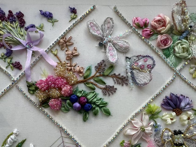 K&ouml;nnte beinhalten: Gestickte Blumenkunst mit einem Lavendelstrau&szlig; mit lila Band, rosa Rosen, einer Libelle und einem Schmetterling. Das Kunstwerk enth&auml;lt Perlenakzente und ist mit Strasssteinen eingefasst.