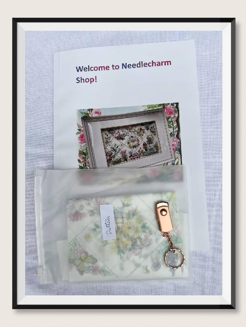 K&ouml;nnte beinhalten: Ein gerahmter Druck mit floraler Stickerei, eine transparente Plastikt&uuml;te mit einem Muster und ein ros&eacute;goldener Schl&uuml;sselanh&auml;nger. Der Druck ist von rosa Rosen umgeben. Der Text "Welcome to Needlecharm Shop!" befindet sich oben im Bild.