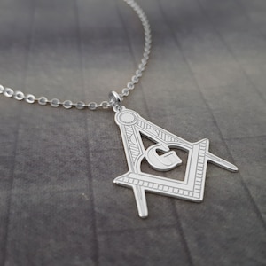 May include: Silver Masonic pendant necklace with a square and compass design. The pendant features a detailed engraving of a level, plumb, and square.