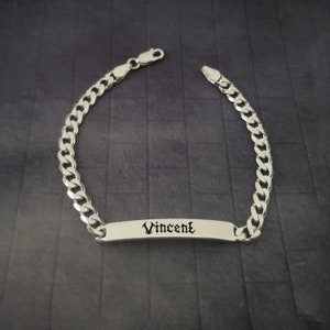 Può includere: Braccialetto a catena curb in argento con una targhetta rettangolare incisa con il nome "Vincent" in font gotico.