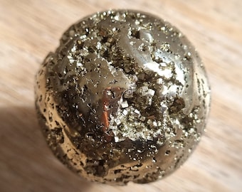 May include: A gold-coloured pyrite sphere with a rough, textured surface. The sphere is made of many small, glittering crystals.