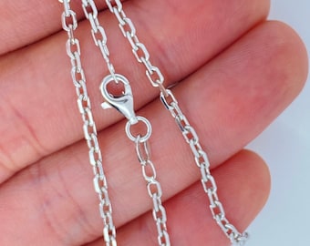 May include: A silver chain necklace with a lobster clasp closure. The chain is made of small, linked oval shapes.