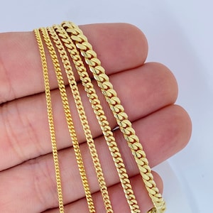 May include: A set of five gold chains of different widths and lengths. The chains are arranged in a fan shape, with the widest chain at the top and the narrowest chain at the bottom.