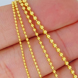 May include: Four gold ball chain necklaces of varying lengths. The chains are made of small, round beads.