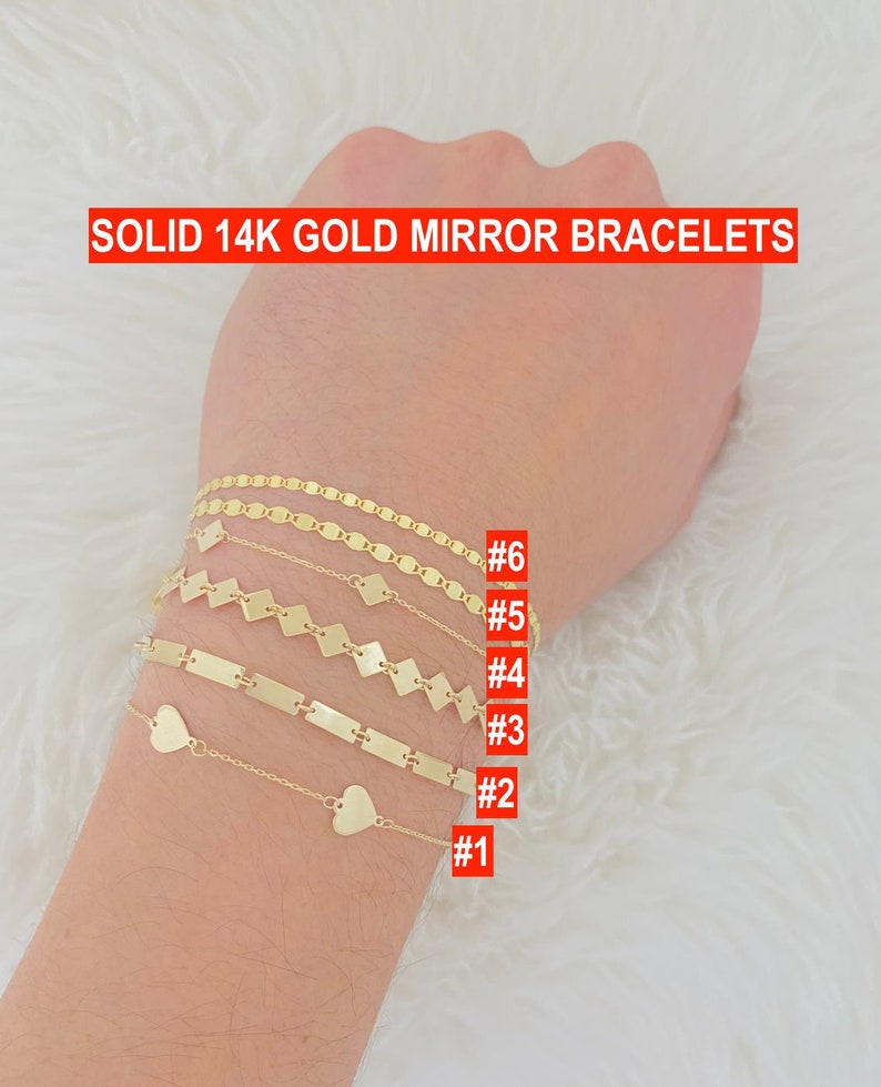 K&ouml;nnte beinhalten: Sechs goldene Armb&auml;nder am Handgelenk einer Person. Die Armb&auml;nder sind von 1 bis 6 nummeriert. Die Armb&auml;nder sind aus 14 Karat Gold gefertigt und haben verschiedene Designs, darunter ein Herz, eine Kette und ein quadratisches Muster.
