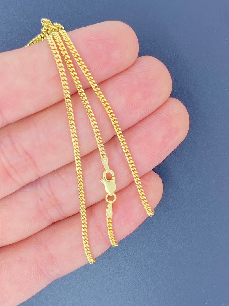 May include: A gold chain necklace with a lobster clasp fastening. The chain is made of a delicate, fine-link design.