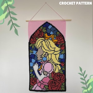 Puede incluir: Un tapiz de pared de ganchillo con una imagen de estilo vitral de una princesa con cabello rubio y un vestido rosa, rodeada de rosas. El fondo es rosa.