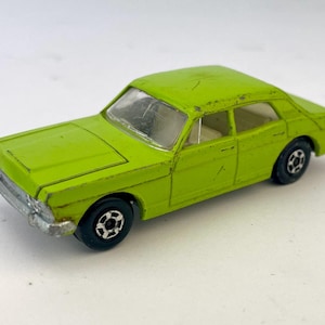 以下が含まれることがあります： ライムグリーンのヴィンテージセダンのおもちゃの自動車モデル。車は詳細なインテリアと黒いグリルを持っています。