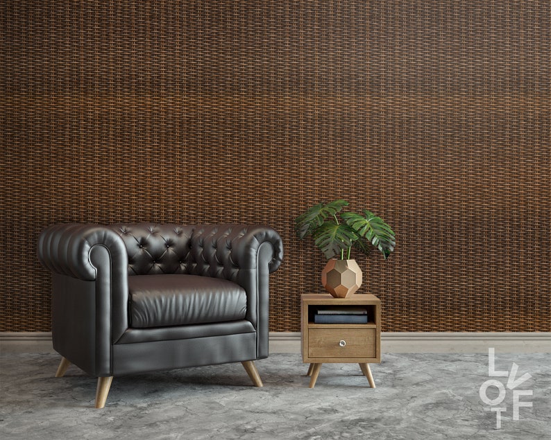 Puede incluir: Un sill&oacute;n de cuero negro con tapicer&iacute;a capiton&eacute; y patas de madera se encuentra frente a una pared con un patr&oacute;n tejido marr&oacute;n. Una peque&ntilde;a mesa auxiliar de madera con un caj&oacute;n y una planta en maceta se encuentra junto al sill&oacute;n.