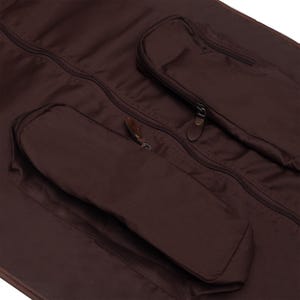 May include: A brown garment bag with two zippered pockets and a brown leather zipper pull.