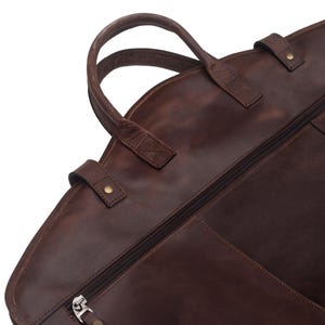 May include: A brown leather garment bag with a zipper closure and a top handle.