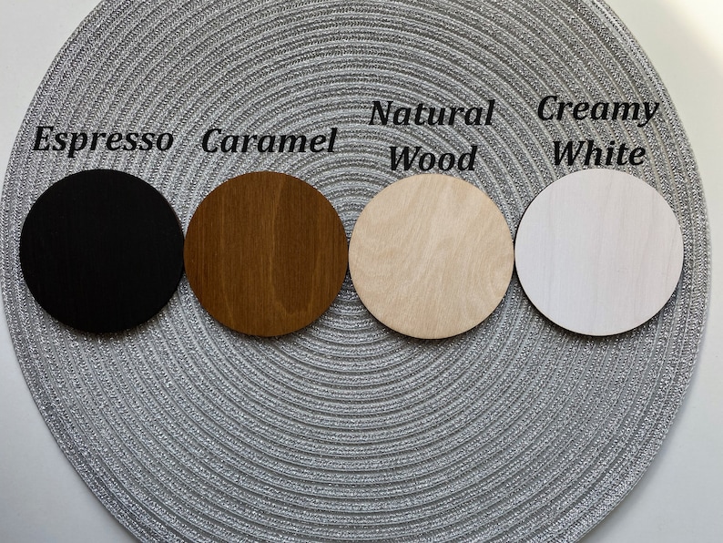 Puede incluir: Cuatro posavasos redondos de madera en diferentes colores: negro, marr&oacute;n, marr&oacute;n claro y blanco. Los posavasos est&aacute;n etiquetados como "Espresso", "Caramelo", "Madera natural" y "Blanco cremoso".