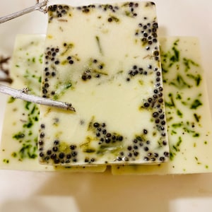 以下が含まれることがあります： 緑と黒の斑点のある白い石鹸が3本。 上の石鹸は斑点模様がより顕著です。