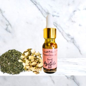 May include: A small glass bottle with a gold cap and a dropper. The bottle is filled with a clear liquid and has a pink label that says "Protection oil Ayaba" with a drum symbol.