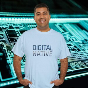 May include: A light blue t-shirt with the words "DIGITAL NATIVE" printed in dark blue and gray. The person is smiling and standing in front of a background with a circuit board design.