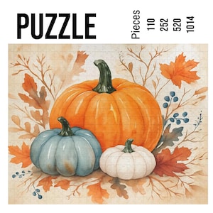 May include: A jigsaw puzzle featuring a watercolor illustration of three pumpkins in shades of orange, blue, and white, surrounded by autumn leaves. The word "PUZZLE" is printed in large black letters. Available in 110, 252, 520, and 1014 pieces.