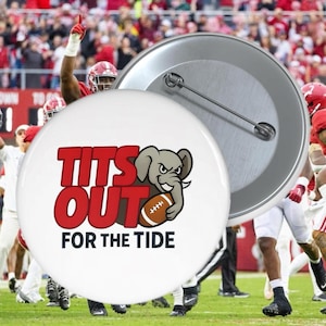 May include: A white button with the text "TITS OUT FOR THE TIDE" in red, with a cartoon elephant holding a football. The background shows a football game with players in red and white uniforms.