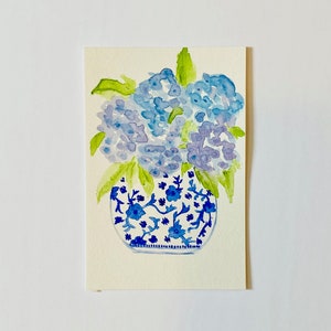 May include: Watercolor painting of a blue and white porcelain vase filled with blue hydrangeas.