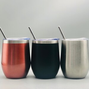 May include: Three stainless steel wine tumblers with lids and straws. The tumblers are in rose gold, black, and silver.