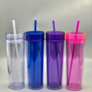 K&ouml;nnte beinhalten: Vier transparente Doppelwandbecher mit farbigen Deckeln und Strohhalmen. Die Becher sind mit einer klaren Fl&uuml;ssigkeit gef&uuml;llt. Die Deckel und Strohhalme sind blau, lila und rosa. Der erste Becher ist transparent mit einem wei&szlig;en Strohhalm.