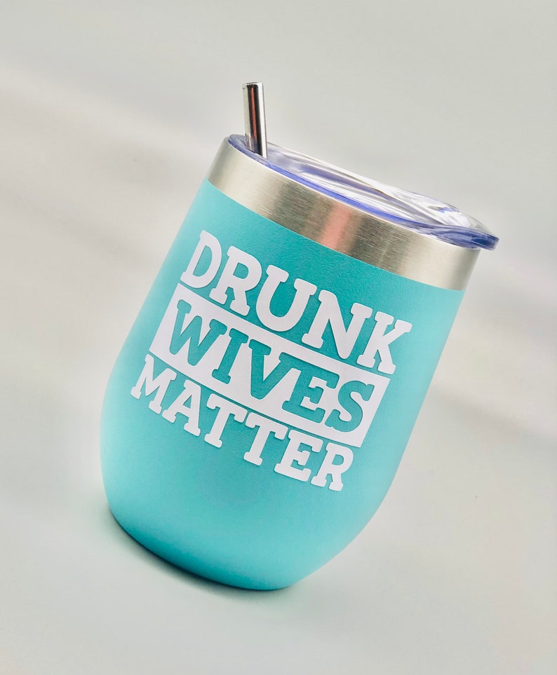 May include: A light blue stainless steel tumbler with a white lid and a straw. The tumbler has the text "DRUNK WIVES MATTER" printed on it.
