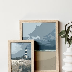 May include: Two framed prints of a lighthouse on a beach with a cloudy sky. The smaller print is in front of the larger print.