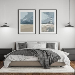 May include: A bedroom with a bed, two nightstands, and two framed prints of seascapes. The bed has a white duvet and a gray throw blanket. The nightstands are black and have two drawers each. The prints are black framed and feature a beach scene and a lighthouse.