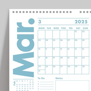 May include: A wall calendar for March 2025, featuring a light blue design. The calendar grid is displayed with dates and days of the week. Includes a section for notes and to-do lists. The word "Mar" is prominently displayed.