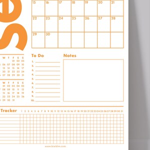 May include: A white and orange planner with a calendar, to-do list, notes section, and tracker. The calendar grid displays dates, and the planner includes the website address www.bialdim.com.