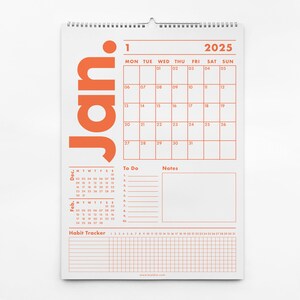 May include: A white 2025 wall calendar with an orange "Jan" graphic. The calendar grid is orange, with sections for "To Do," "Notes," and a habit tracker. The calendar is spiral-bound at the top.