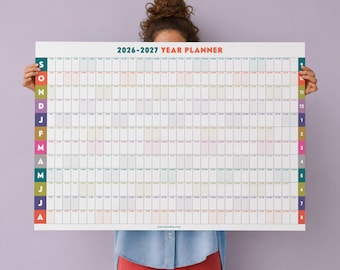 May include: A large 2026-2027 year planner wall calendar featuring a grid layout with months listed vertically in colored blocks on the left and right sides. The calendar includes days of the week and dates in a clean, organized format on a white background.