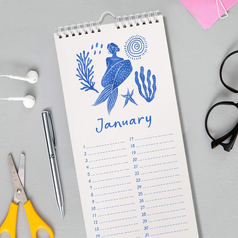 May include: A spiral-bound calendar featuring a blue mermaid illustration and the month of January. The design includes aquatic elements like seaweed and a starfish. The calendar has a white background with a grid for daily entries.