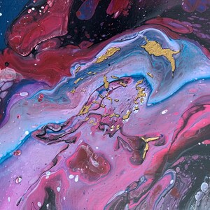 以下が含まれることがあります： ピンク、パープル、ブルー、ブラックのペイントが渦巻く抽象画。絵画は、金色のアクセントが施された銀河のような外観をしています。
