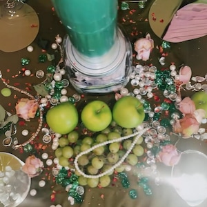 Peut inclure: Une bouteille en verre vert avec un couvercle blanc est pos&eacute;e sur une table entour&eacute;e de perles vertes et blanches, de perles et de pommes vertes. On y trouve &eacute;galement des fleurs roses et un tissu ray&eacute; rose et blanc.