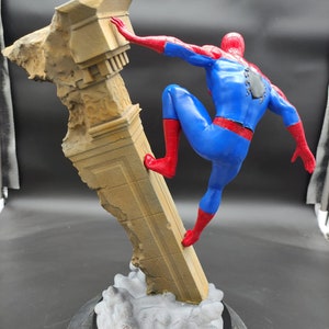 Pu&ograve; includere: Una action figure di Spider-Man che scala un pilastro di pietra rotto. La figura &egrave; in una posa d'azione dinamica con una gamba sollevata e l'altro piede piantato sul pilastro. La figura &egrave; su uno sfondo grigio.