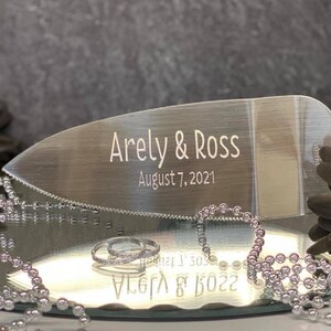 May include: Silver cake server with a serrated edge, engraved with the names "Arely & Ross" and the date "August 7, 2021".