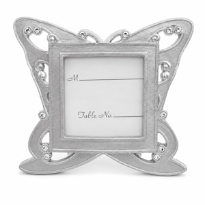 May include: A silver-toned metal place card holder shaped like a butterfly with clear crystal accents. The centre square features a white insert with the printed text M. and Table No. followed by horizontal lines for writing names and numbers.