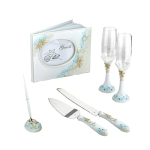 Może przedstawiać: Zestaw ślubny z motywem plażowym. Zawiera księgę gości, dwa kieliszki do szampana, nóż i łopatkę do ciasta oraz długopis. Elementy są białe z niebieskimi akcentami i dekoracjami z muszli.