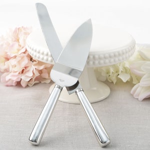 Puede incluir: Un juego de cuchillo y servidor para pastel de plata con un borde dentado en el cuchillo y un borde liso en el servidor. Los mangos son de plata y tienen un diseño texturizado.