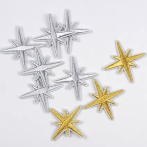 May include: A collection of ten iron-on patches featuring star shapes. Five of the patches are gold and five are silver.