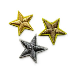 May include: Three embroidered star patches, one silver and two gold, on a white background.