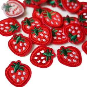 May include: A collection of red embroidered strawberry patches with white seeds and green leaves.