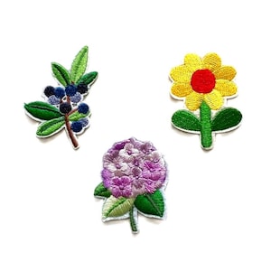 May include: Three embroidered iron-on patches featuring a purple hydrangea, a yellow flower with a red center, and a green branch with blue berries.