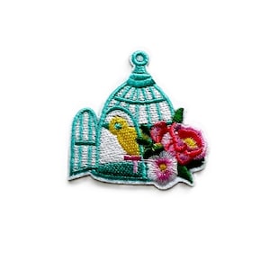 May include: An embroidered iron-on patch featuring a turquoise birdcage with a yellow bird inside and pink and white flowers.
