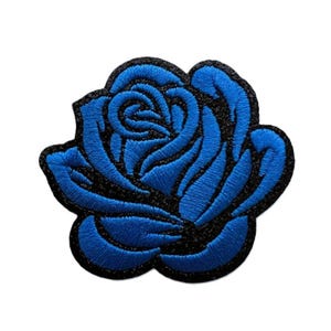 May include: An embroidered patch in the shape of a blooming rose. The flower petals are rendered in a vibrant blue thread, while the outlines and the base of the rose are defined by thick, contrasting black stitching throughout the design.