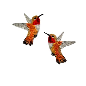 May include: Two embroidered hummingbird patches in orange, red and white. The hummingbirds are in flight with their wings spread.