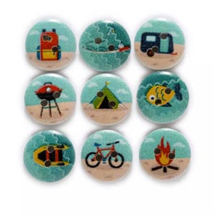 May include: Nine round wooden buttons with different camping and outdoor activities printed on them. The buttons are turquoise blue with a white sandy beach background. The designs include a tent, a campfire, a fish, a bike, a grill, a boat, a camper, a backpack, and a surfboard.