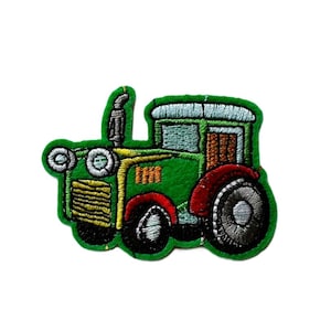 May include: Embroidered patch depicting a green tractor with black wheels and a red tyre. The tractor features yellow and blue details, and a silver exhaust pipe. The patch is set against a white backdrop.